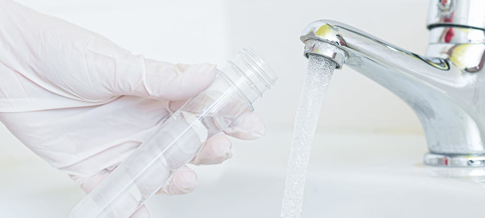 Person filling a glass with water from the tap