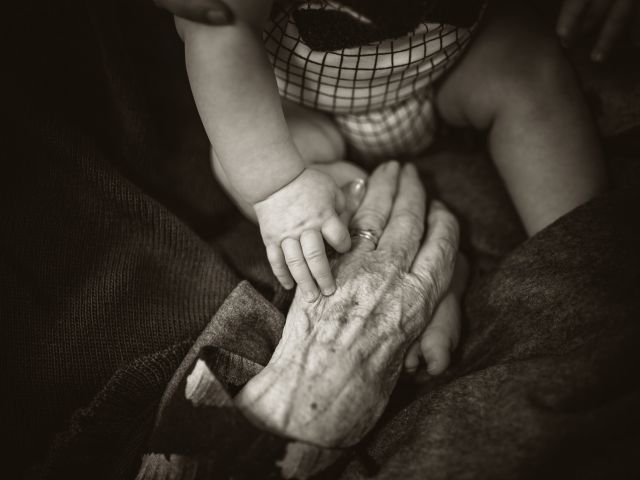 Baby and grandparent touching hands